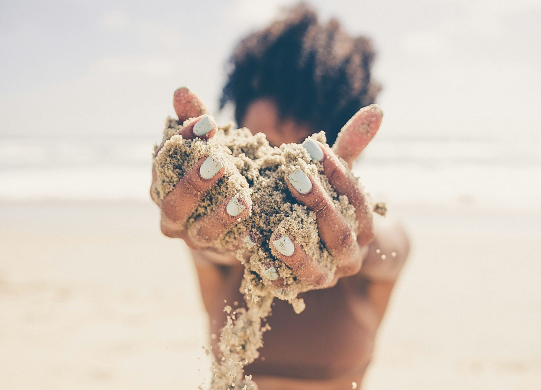 close-up of hands holding sand on the beach
