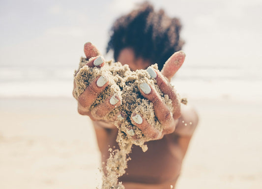 close-up of hands holding sand on the beach